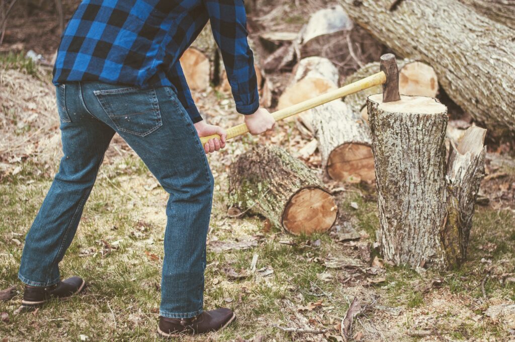 man cutting wood with an ax during the daytime